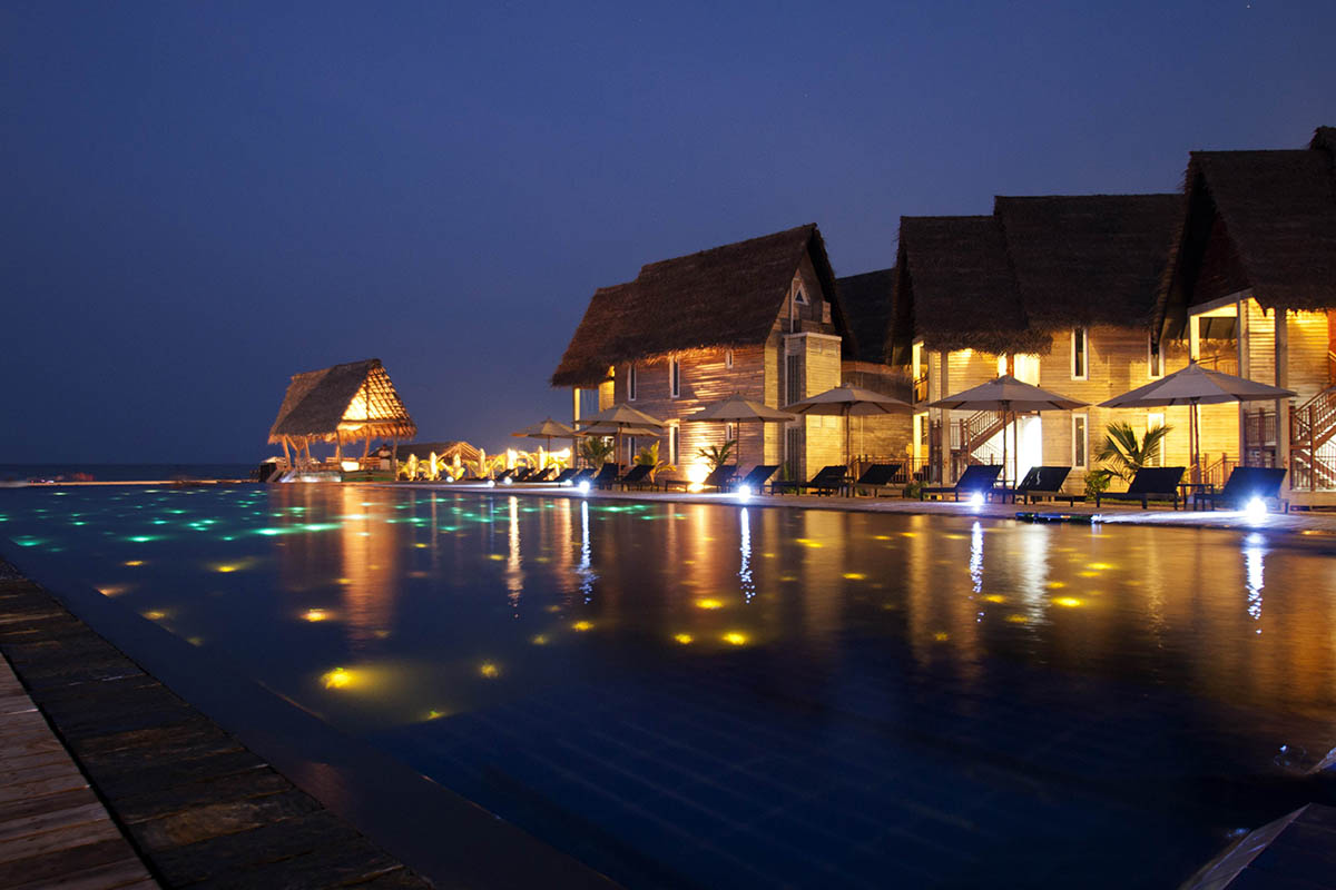 The infinity pool lit at night in front of the chalets