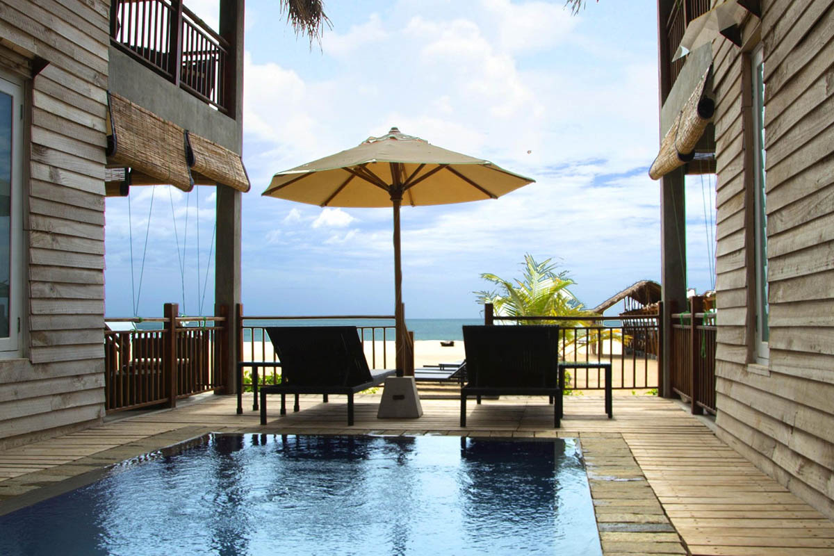 An Ocean Suite deck with loungers and a parasol beside a plunge pool, facing the sea
