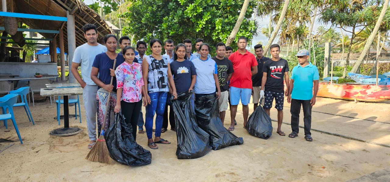 Group of volunteers posing after beach cleanup with trash bags - Beach Cleanups With Weligama Hotels