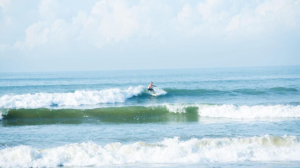 Beginner surfer riding a small wave during a surf session in the morning hours at Weligama Bay