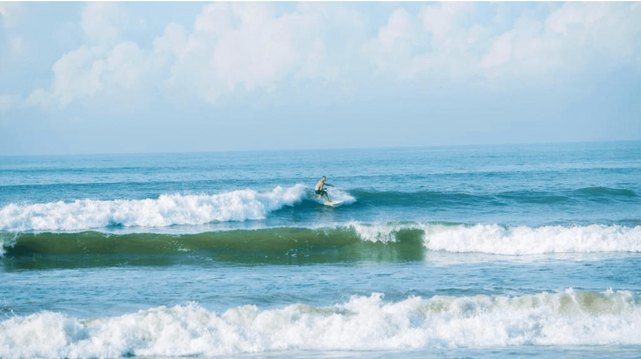 Single surfer riding a wave at Weligama beach.