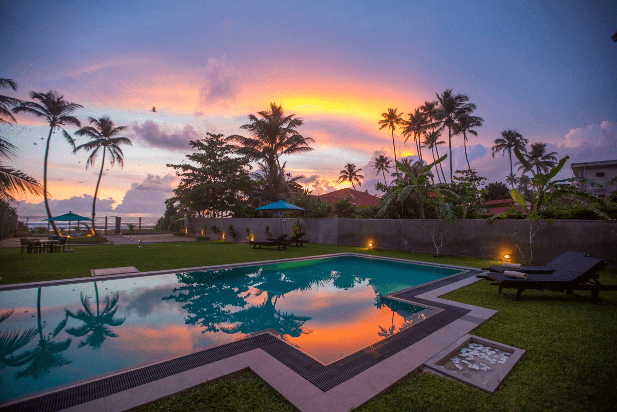 Parangi Weligama Bay's pool and beachfront at golden hour.