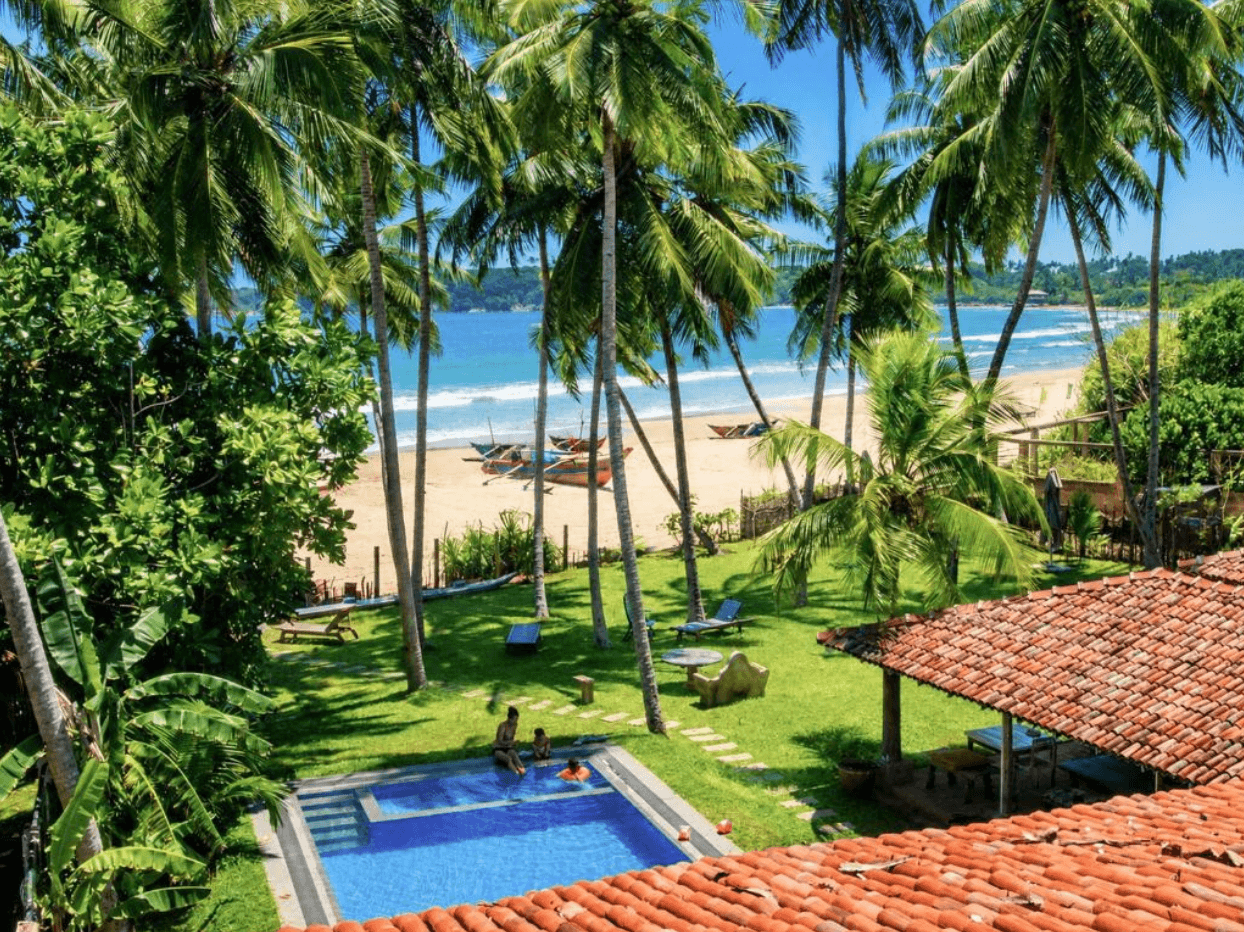 Deewara's pool and garden overlooking the beach with fishing boats in Mawella