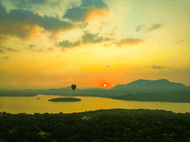 Hot air balloon rising over Kandalama Lake at sunrise